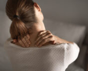 woman is holding neck with both hands as if in pain