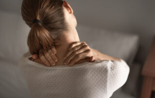 woman is holding neck with both hands as if in pain