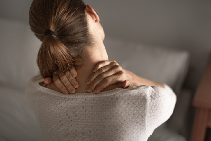 woman is holding neck with both hands as if in pain